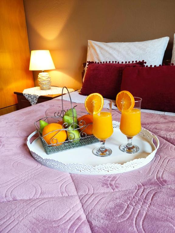 a tray of fruit on a bed with two glasses of orange juice at Room Ntina Kastraki in Kastraki
