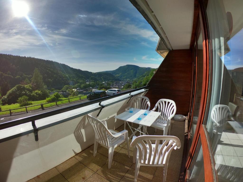 a balcony with a table and chairs and a view at Appartement T2 45m² avec terrasse - 4/6 personnes in Le Mont-Dore