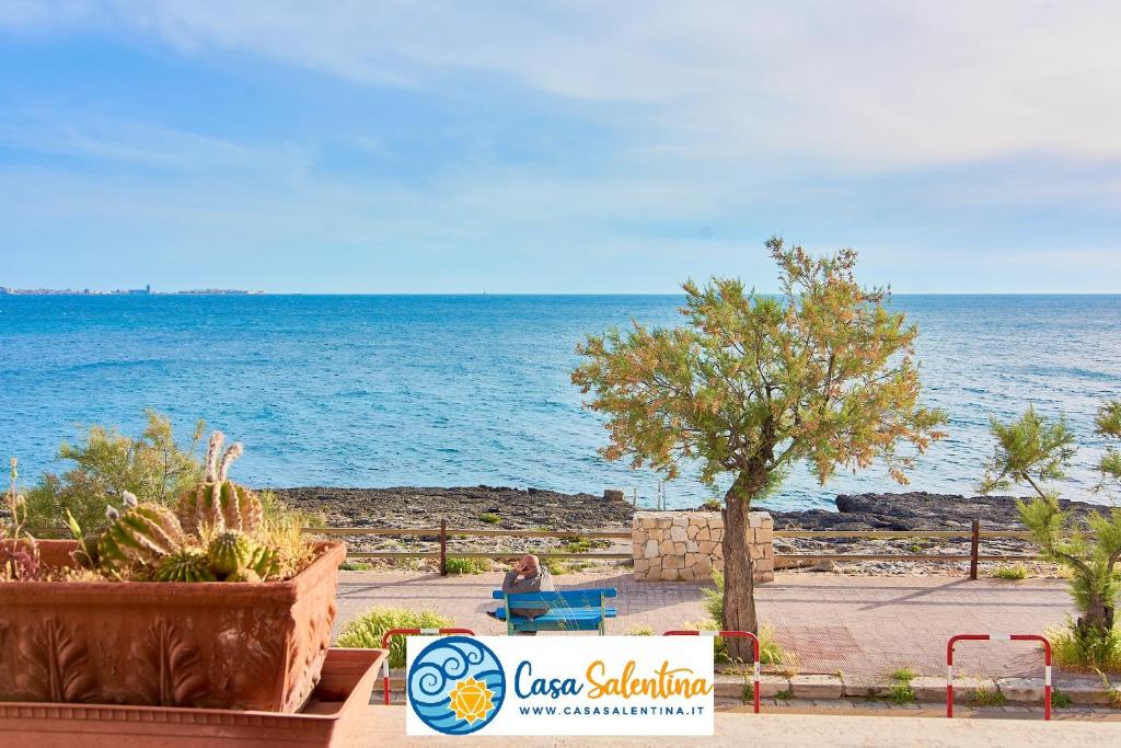 a person sitting on a bench next to the ocean at CasaSalentina - Lido Conchiglie in Lido Conchiglie