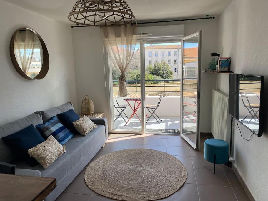 un salon avec un canapé bleu et une grande fenêtre dans l'établissement Cosy T3 gare Terrasse + parking, à Sète
