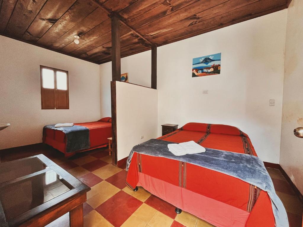 a bedroom with two beds and a table in a room at Anexo By Hotel Maya Ik' in Antigua Guatemala