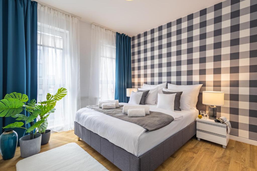 a bedroom with a large bed with blue curtains at Apartment Dąbrowskiego by The Railway Station Wroclaw in Wrocław