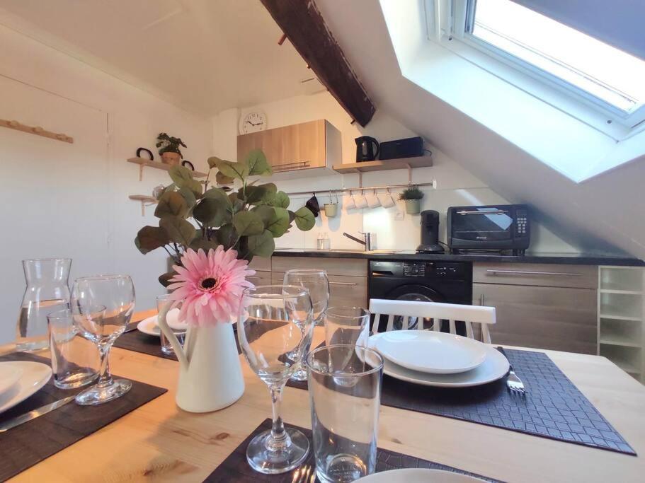 a kitchen with a table with glasses and a vase with a flower at Equidia Compiègne Free Parking Wifi Self Check-in in Venette