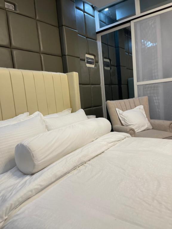 a bedroom with two white beds and a chair at Vitasolo Hometel & Suite in Tagum