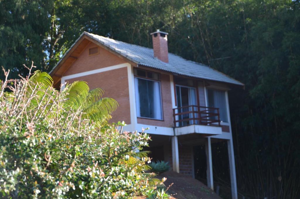 a small house with a porch and a balcony at Chalé Recanto do Sol in Paraisópolis