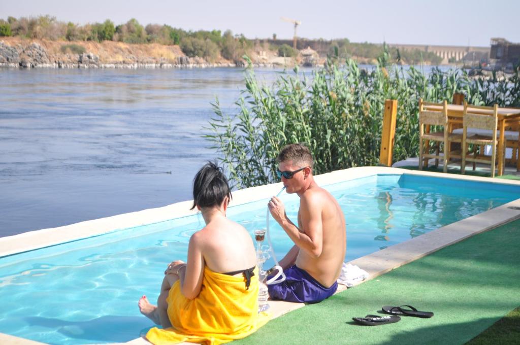 a man and a woman sitting next to a swimming pool at Fenti Nubian Resort in Aswan