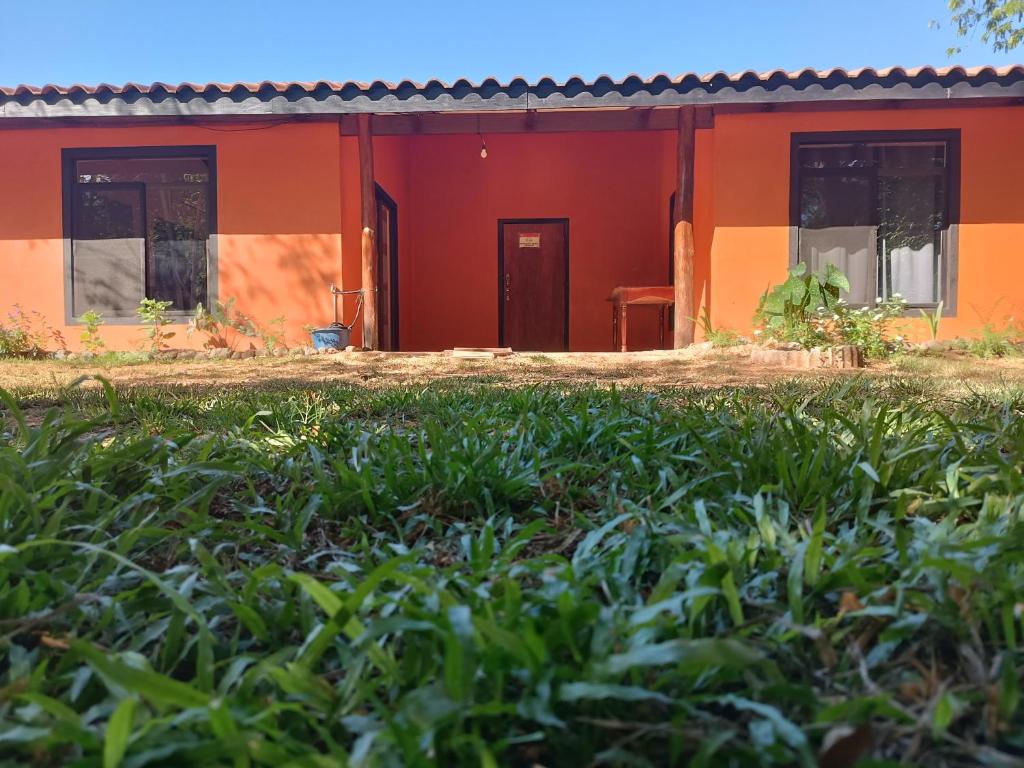 een oranje huis met een groen veld ervoor bij House Manantial de Vida in Nandayure