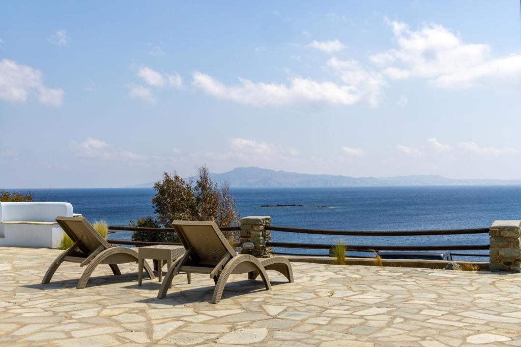 2 stoelen op een patio met uitzicht op de oceaan bij White Holidays Project Ag. Sostis in Agios Sostis