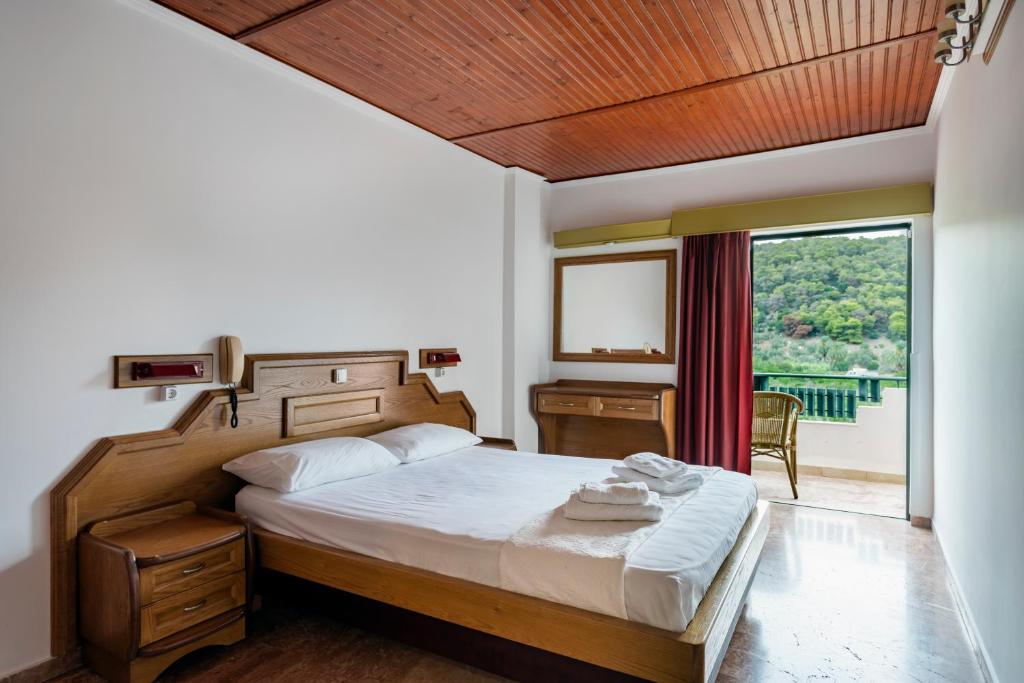 a bedroom with a bed and a large window at Binji Hotel in Ancient Epidavros