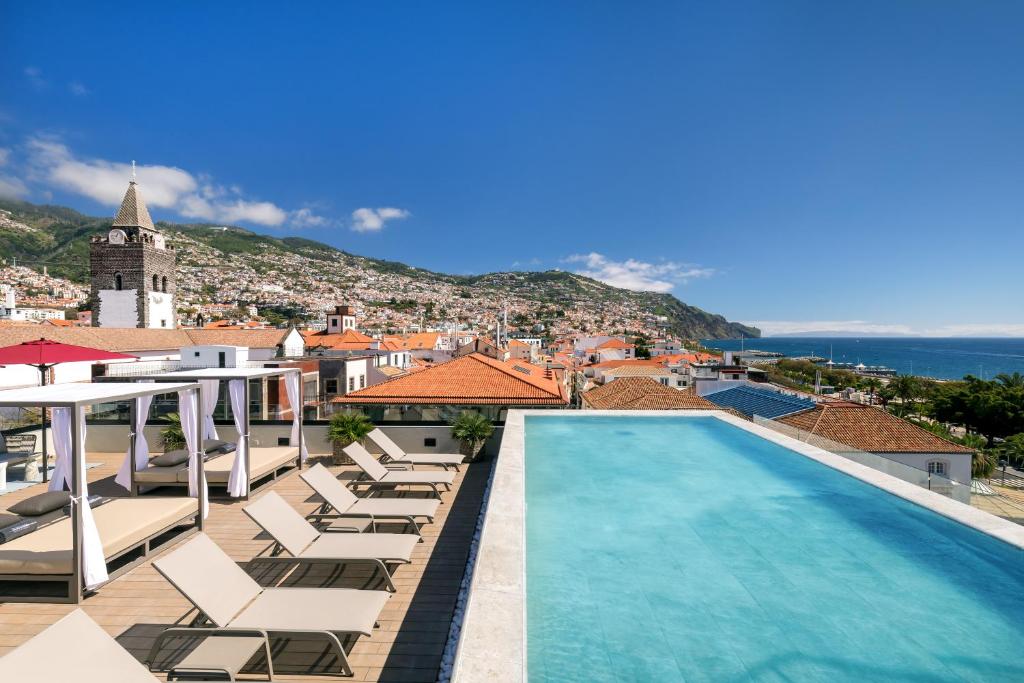 a pool on the roof of a building with lounge chairs at Barceló Funchal Oldtown in Funchal