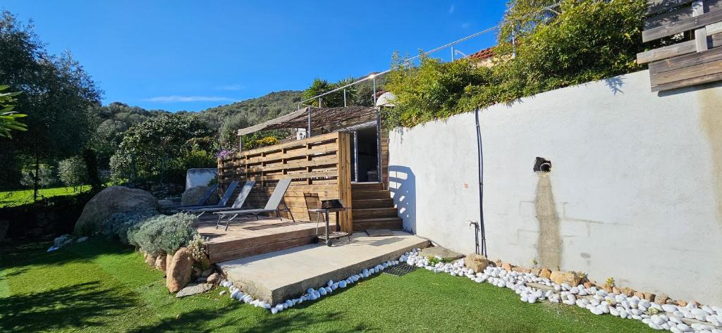 una casa con un jardín con un banco en el césped en Mini villa T3 climatisée, vue mer, cosy & moderne, en Olmeto