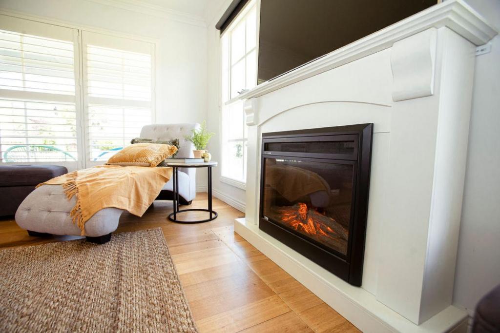 a living room with a fireplace and a bed at Beachside Getaway Bay Views North Shore VIC Sleeps 12 Free Wifi in North Shore
