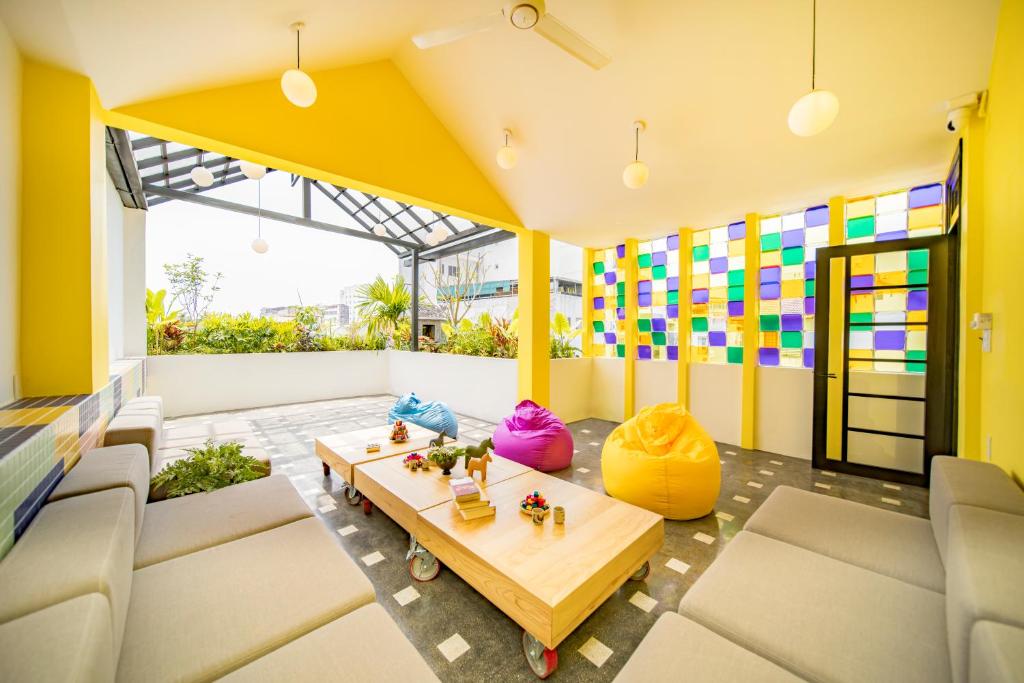 een woonkamer met gele muren en een tafel en stoelen bij BÁNH INN in Hue