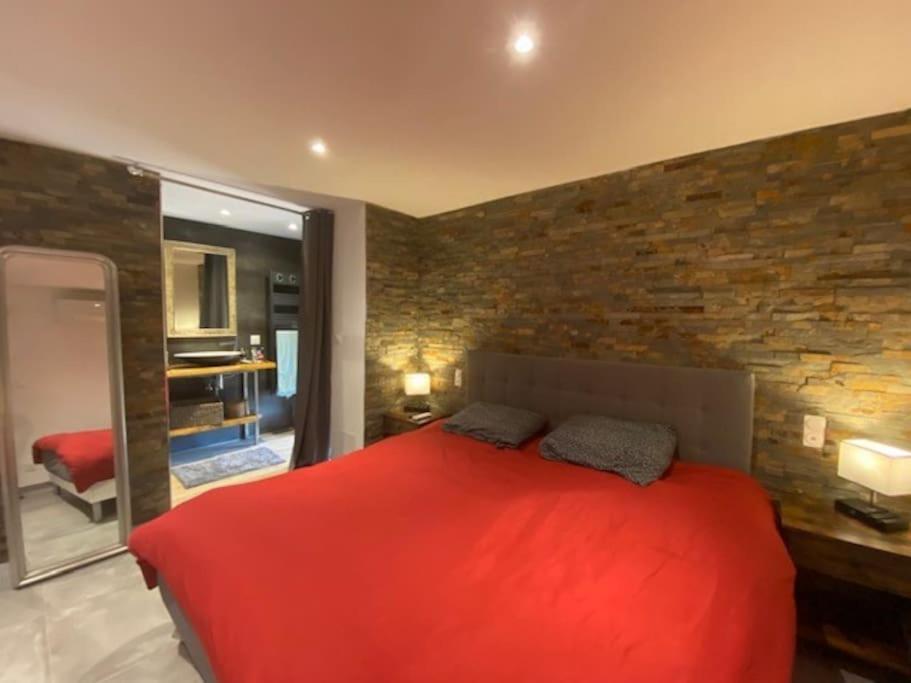 una camera con un letto rosso e un muro di mattoni di Maison de caractère, Zilia, au pied du Montegrossu a Zilia
