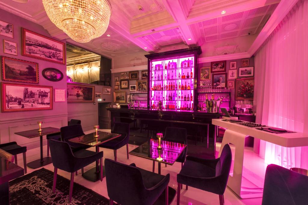a bar with purple lighting in a room with tables and chairs at Vertigo Hotel, By Marriott, a Member of Design Hotels in Dijon