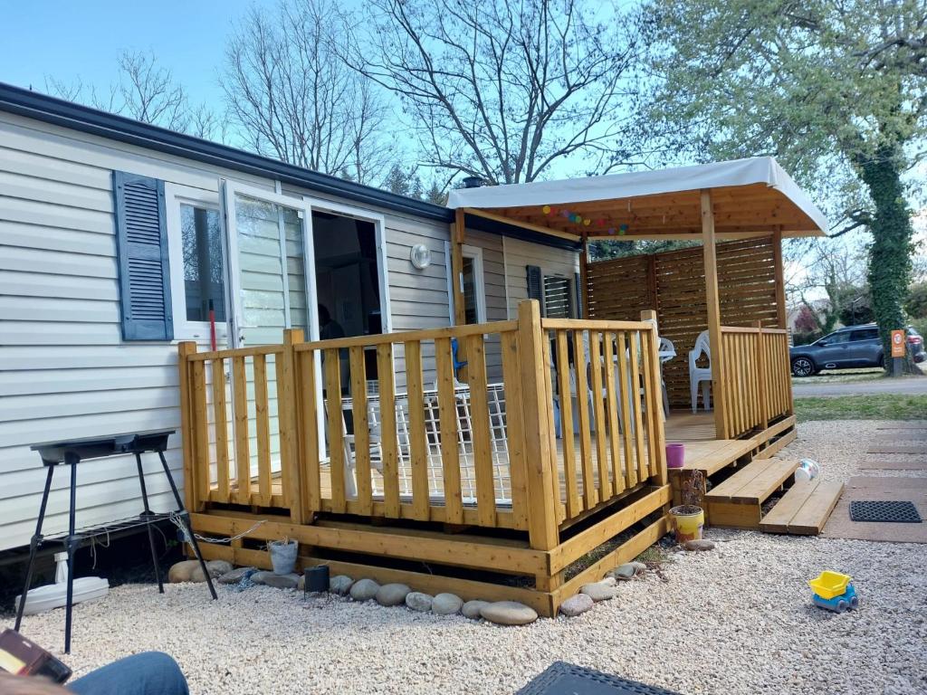 une maison avec une terrasse couverte et une terrasse en bois dans l'établissement mobil home tout confort 6 personnes climatisé au pied du Luberon, à La Roque-dʼAnthéron