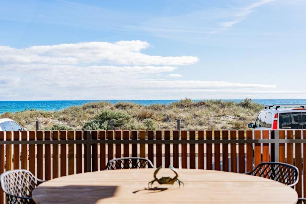 uma mesa e cadeiras num deque com praia em Luxury Beach Front Apartment Moana - Waterviews em Moana