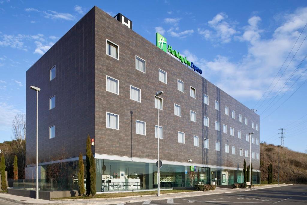 a large brick building with a green sign on it at Holiday Inn Express Pamplona, an IHG Hotel in Mutilva Baja