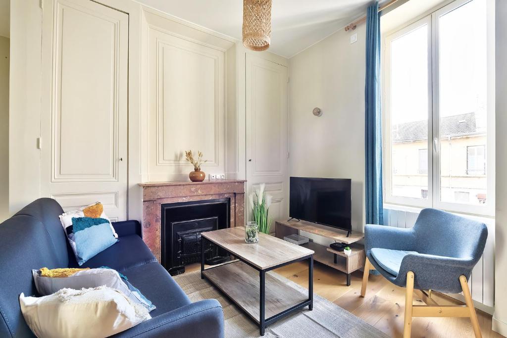 sala de estar con sofá azul y chimenea en Appartement Le Somptueux - Idéalement Situé, en Caluire-et-Cuire