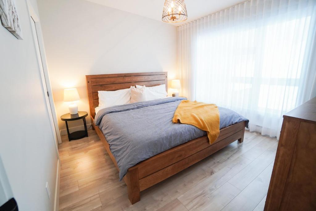 1 dormitorio con 1 cama con cabecero de madera en Le Riverain - Condo neuf au bord de l'eau, en Shawinigan
