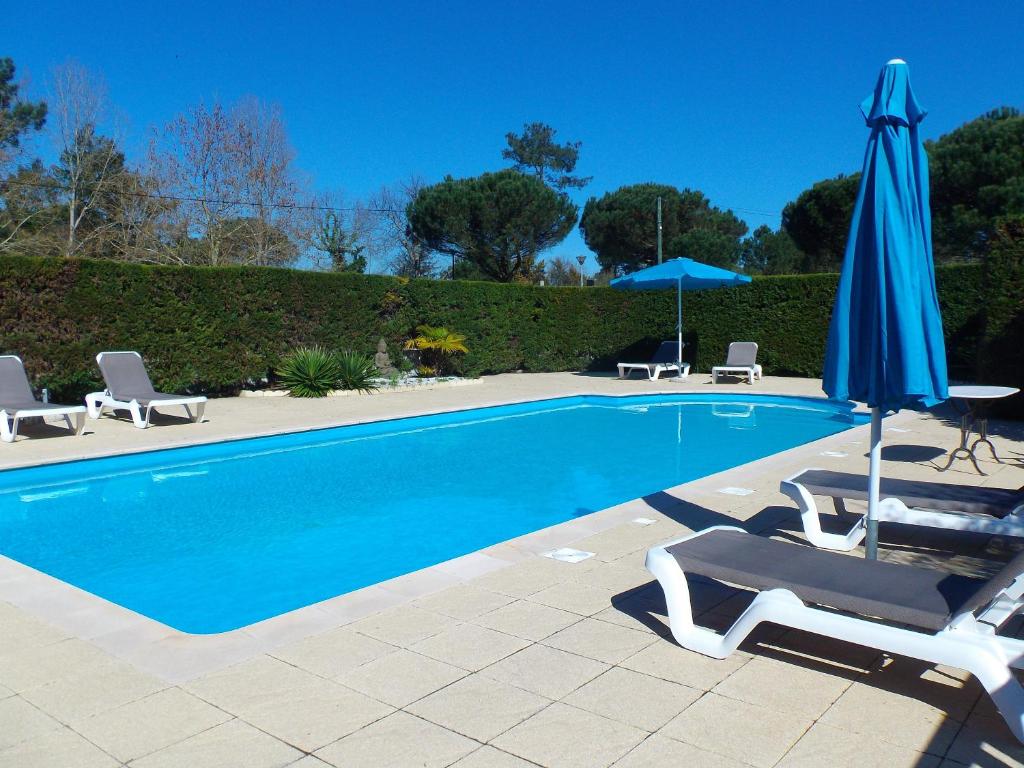 a swimming pool with two chairs and an umbrella at Hotel Cote et Lac in Biscarrosse