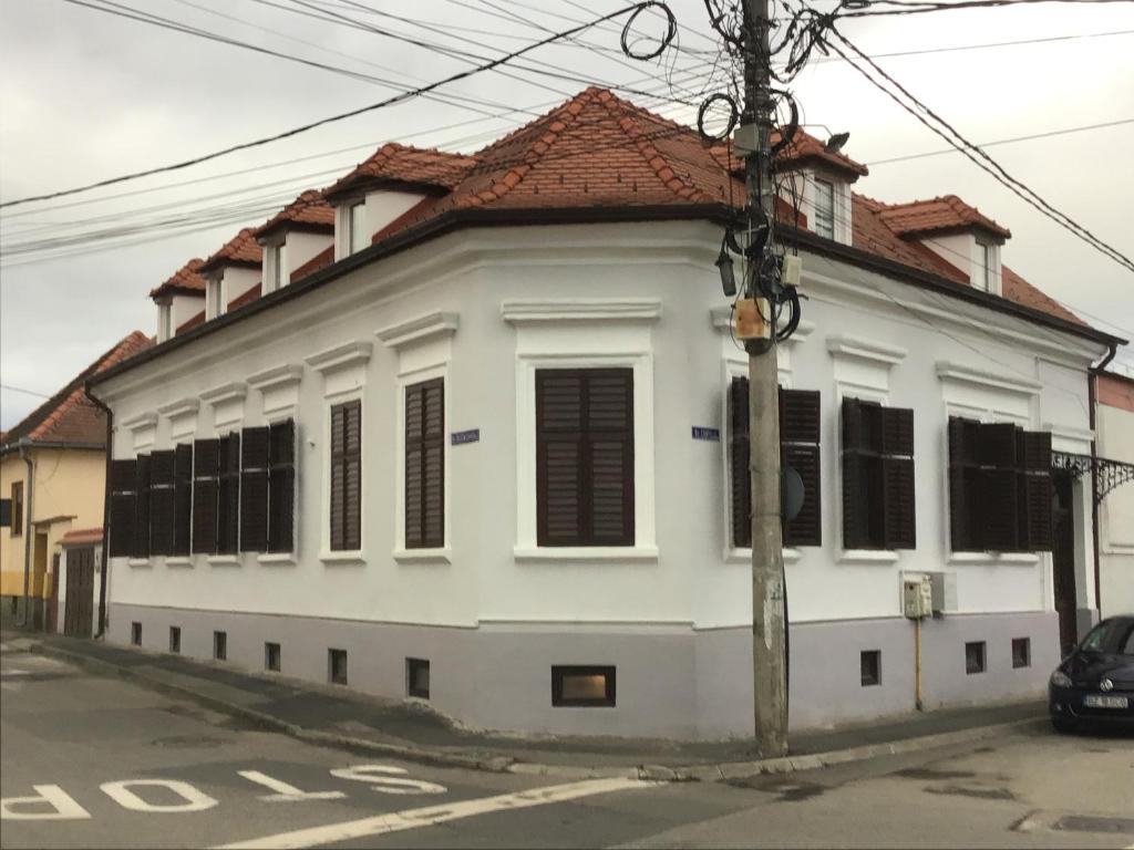 um edifício branco com um telhado vermelho numa rua em Casa Wagner em Sibiu