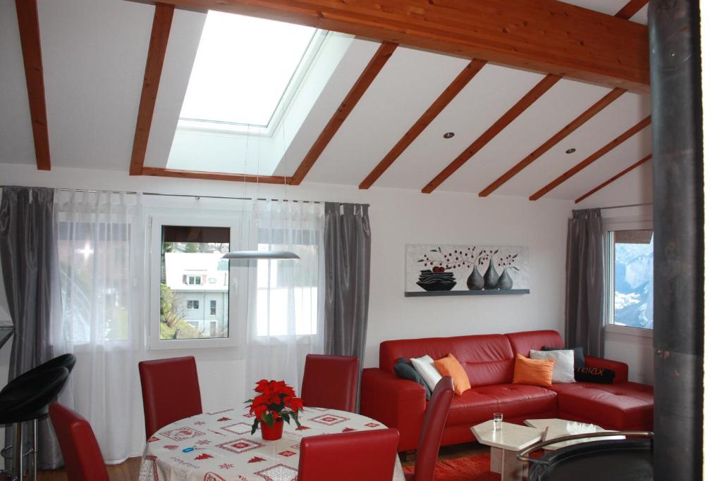 a living room with a red couch and a table at Chalet Gerbera in Wengen