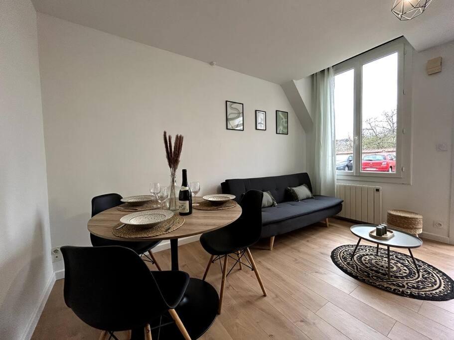 a living room with a table and chairs and a couch at Logement Neuf - Proximité Centre in Bourges