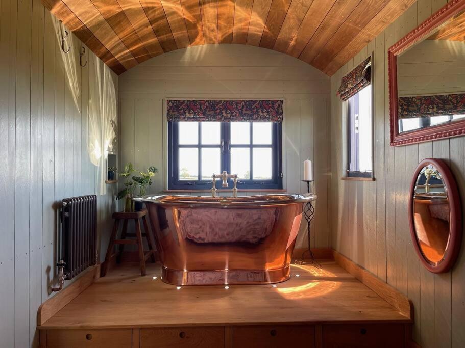 a large wooden tub in a room with a window at Novelist Shepherd's hut in Beaminster