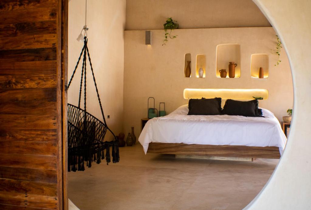 1 dormitorio con cama y espejo redondo en BH Hotel & Cenote Tulum - Adults Only en Tulum