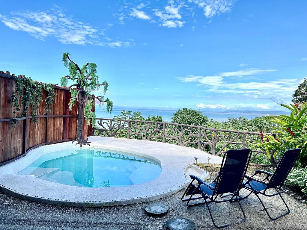 a swimming pool with two chairs and a table at Akua Suites Ocean View in Tarcoles