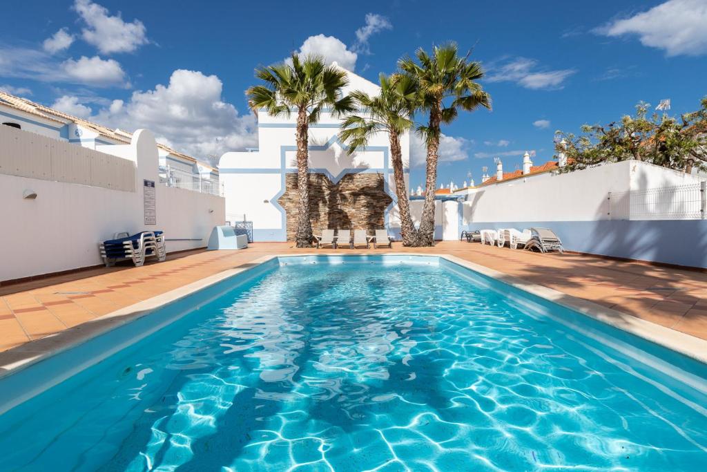 una piscina en la azotea de una casa con palmeras en Villa Turquesa By ALGARVEMANTA, en Manta Rota