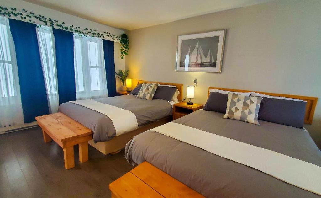 Duas camas num quarto com paredes e janelas azuis em Lofts Fleuve et Montagnes em Sainte-Anne-de-Beaupré