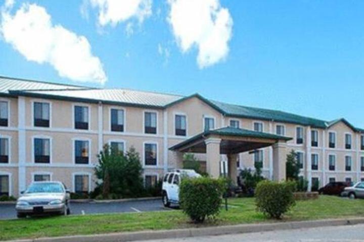 un grand bâtiment avec des voitures garées dans un parking dans l'établissement ARK SUITES, à Jonesboro