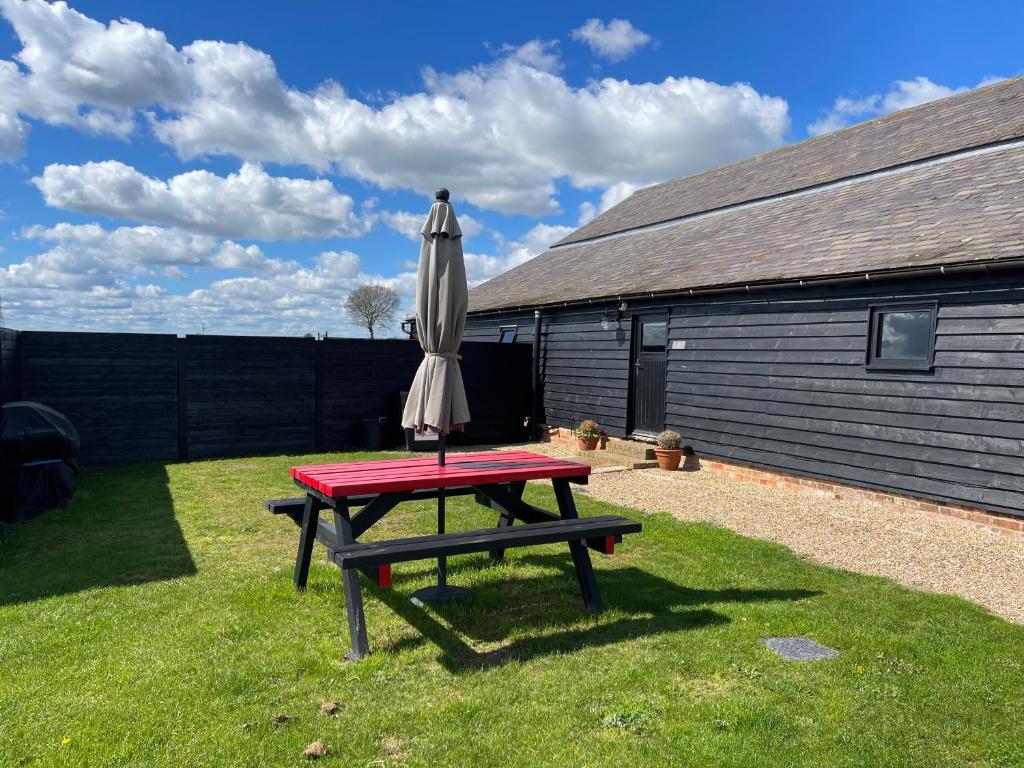 a picnic table with an umbrella and a picnic table at The Cow Shed 2-Bed Apartment in Bradwell on Sea in Bradwell on Sea