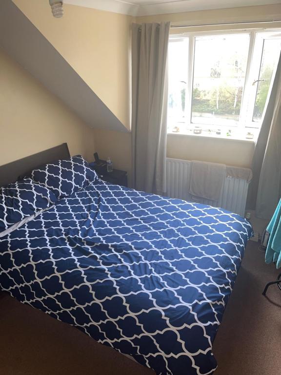 a bedroom with a blue comforter on a bed with a window at The Croydon Road house in Elmers End