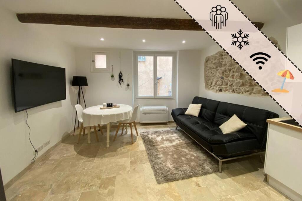 un salon avec un canapé noir et une table dans l'établissement Charmant deux pièces dans le vieil Antibes Safranier, à Antibes