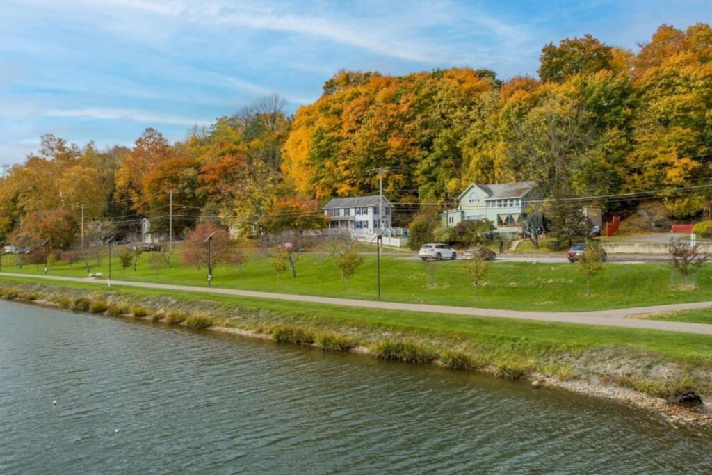 a road next to a river with houses and trees at River Front Home in the Heart of Ithaca in Ithaca