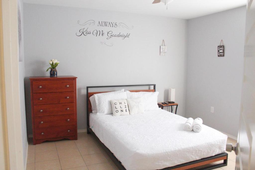 a bedroom with a bed and a dresser with a sign on the wall at Casa Roble. Downtown Brownsville in Brownsville