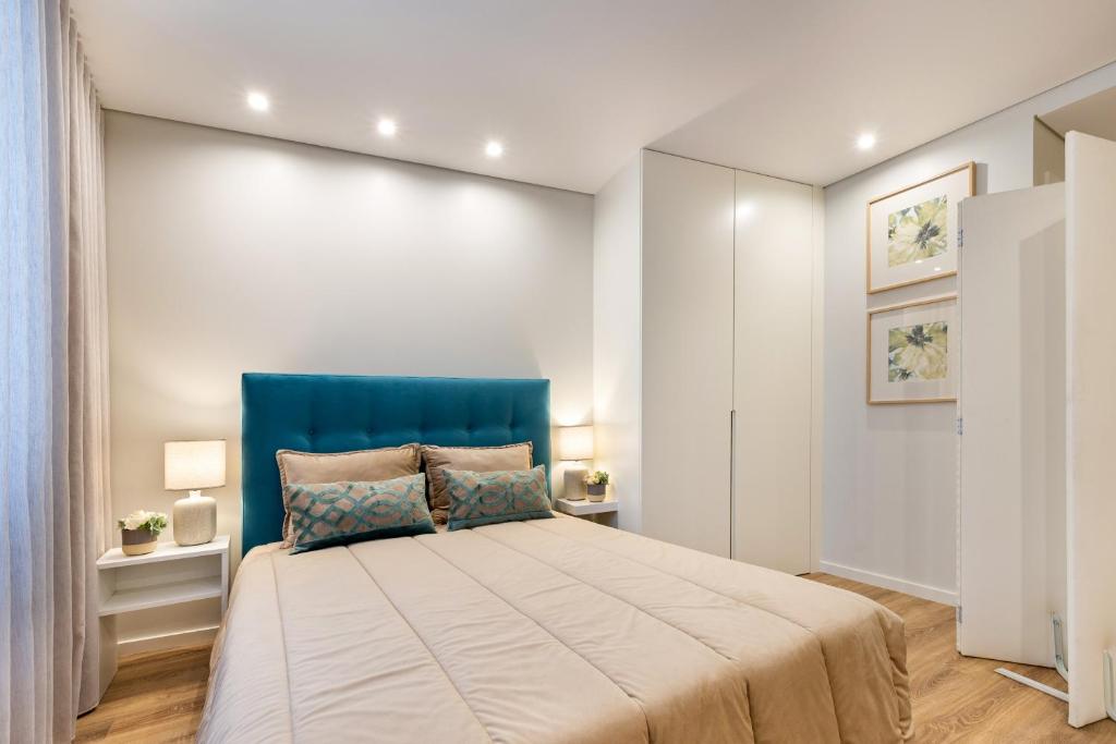 a bedroom with a large bed with a blue headboard at Sé Apartamentos - Niko Apartment in Braga