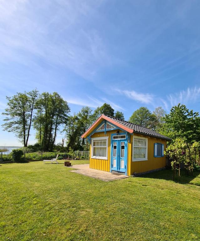 a small yellow and blue shed in a yard at Ferienbungalows am See in Altfriesack