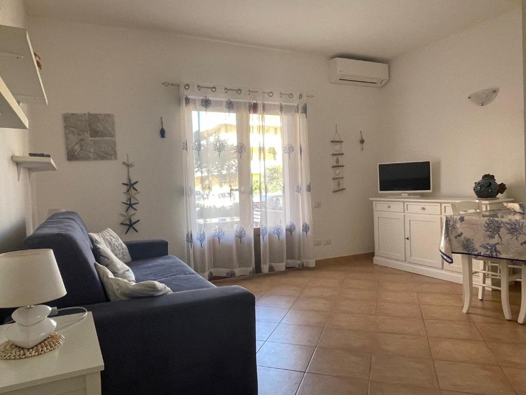 uma sala de estar com um sofá azul e uma televisão em Case del Mar em Santa Teresa Gallura