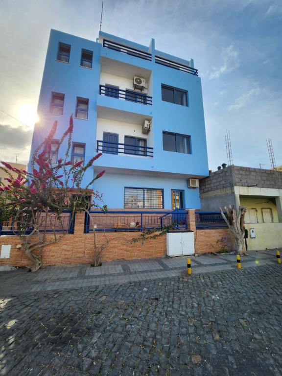 a tall blue building in front of a brick building at Txada Hostel in Praia