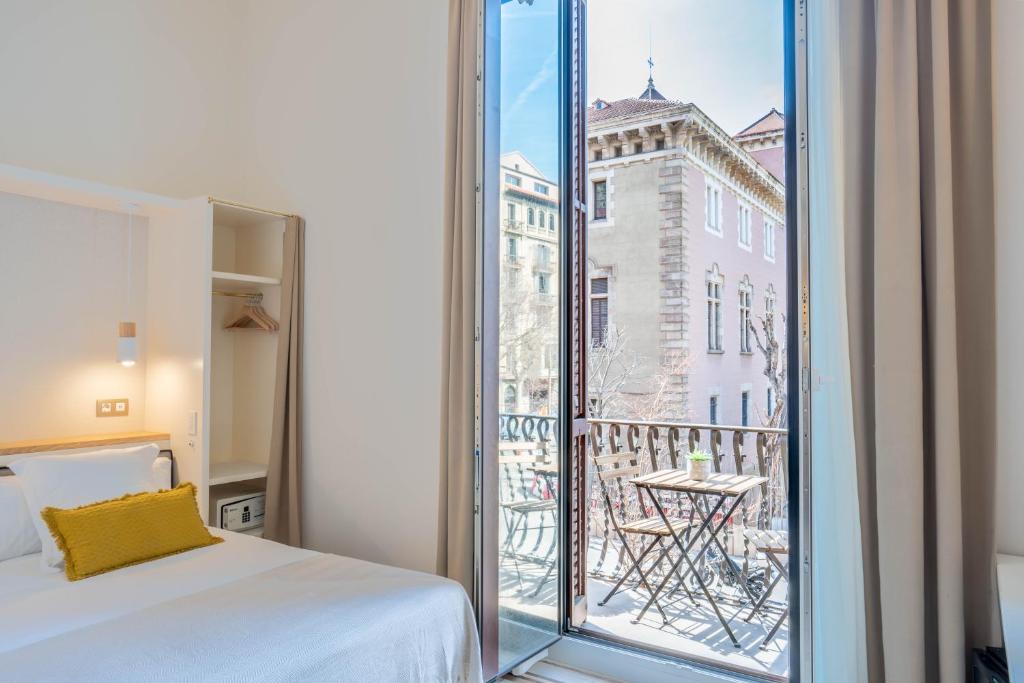 a room with a bed and a balcony with a view at Feelathome Casa Bertrand in Barcelona