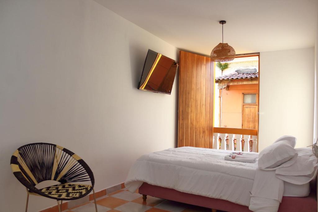 a bedroom with a bed and a chair and a window at Hostal Casa Torres Centro Historico - Adults Only in Cartagena de Indias