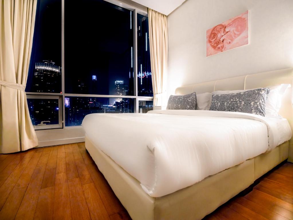 uma grande cama branca num quarto com uma grande janela em Soho Suites KLCC by Alucard's Cat em Kuala Lumpur