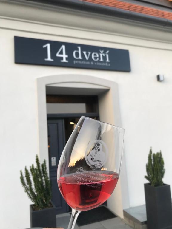 a glass of red wine sitting in front of a building at Hotel 14Dveří in Drnholec