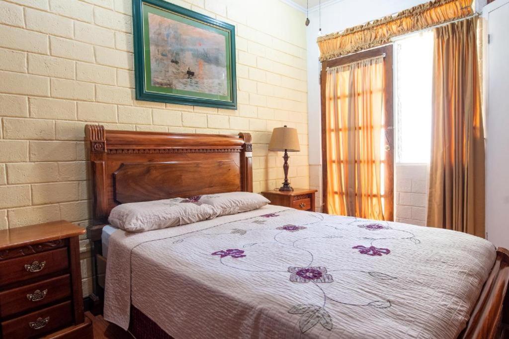1 dormitorio con cama y pared de ladrillo en Sura Bed and Breakfast, en San José