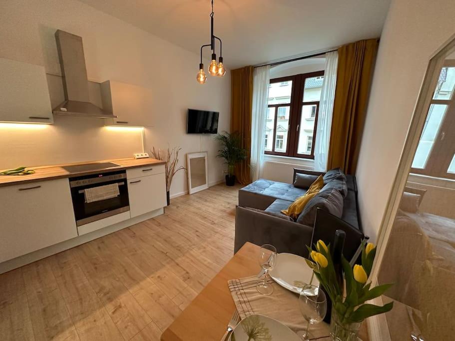 a living room with a couch and a table and a kitchen at Herrliches wohnen mit Teichblick in Altenburg