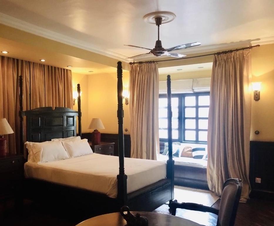 a bedroom with a bed with a ceiling fan at Courtyard Pujan Hotel in Kathmandu